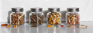 LIFA LAB whole food supplements natural organic glass bottles sitting on white marble table with white background with capsules filled turmeric, saffron, cardamom, rose powder, sumac, rose petal, garlic, ginger, dill, rosemary acai, desiccated coconuts   